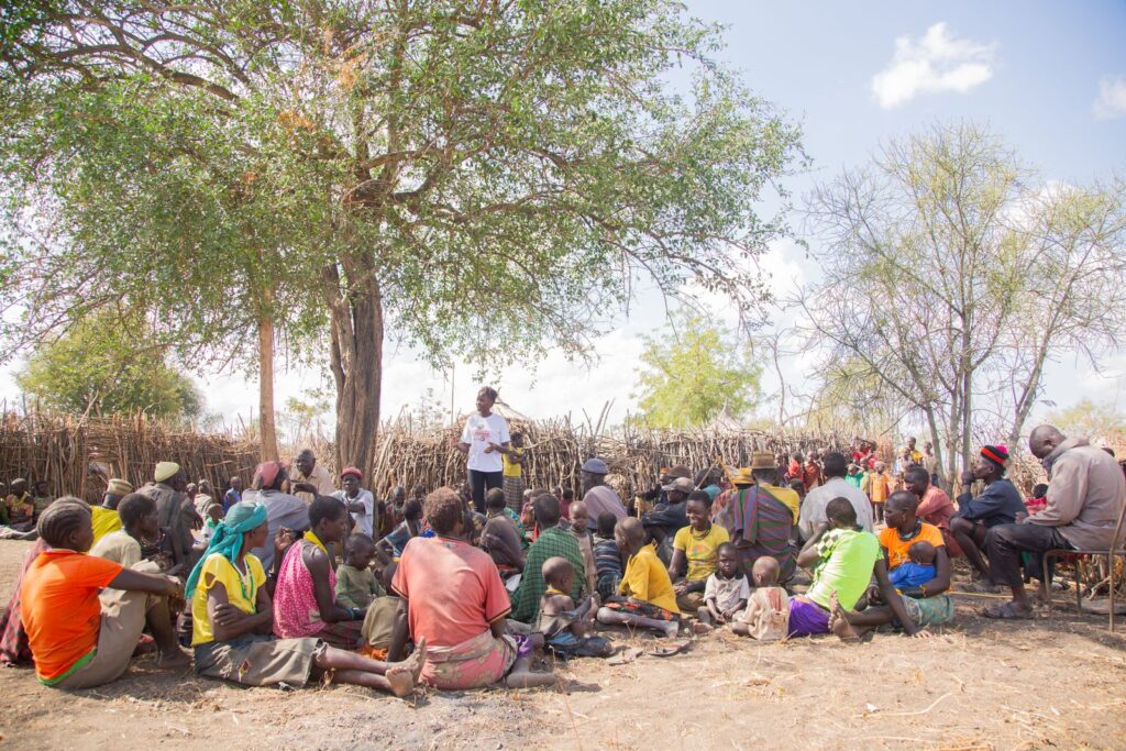 Community members gathered under a tree for a village meeting