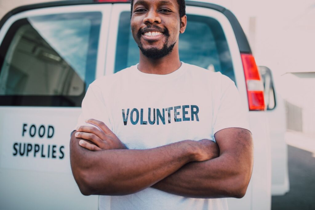 Smiling volunteer beside a community food-supplies van